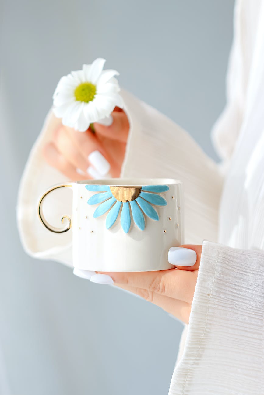 close up of woman holding a ceramic cup with a flower
